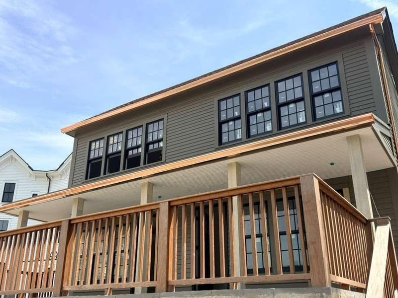 Copper gutter running the roofline of a grey clapboard house and along the porch eaves below