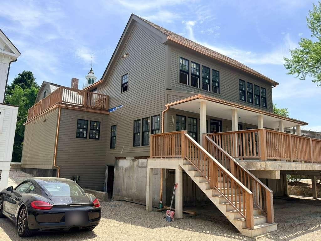 The whole rear elevation of the house with copper gutters along both roof lines and a copper downspout at the corner