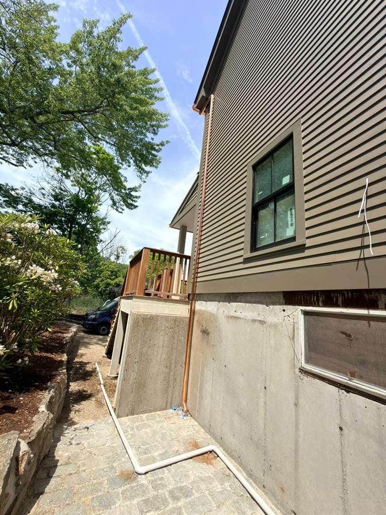Copper downspout carried down the corner of the house past the foundation wall