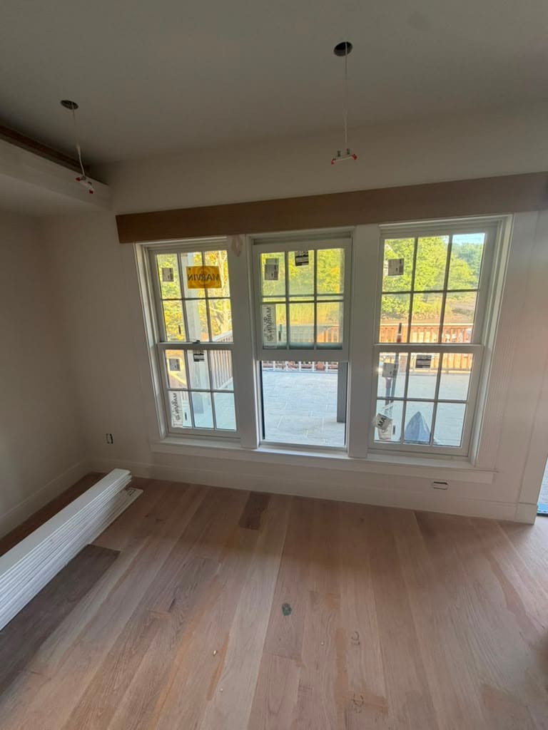 Oak floor running up to the trim under a bank of three windows