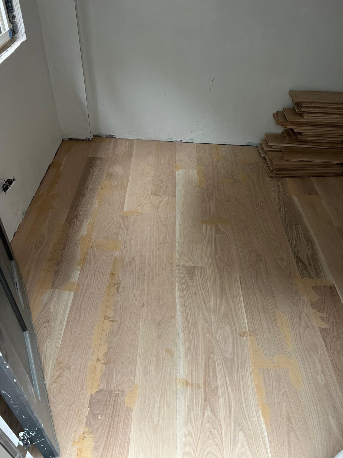 Floor part laid, the remaining boards stacked ready against the wall