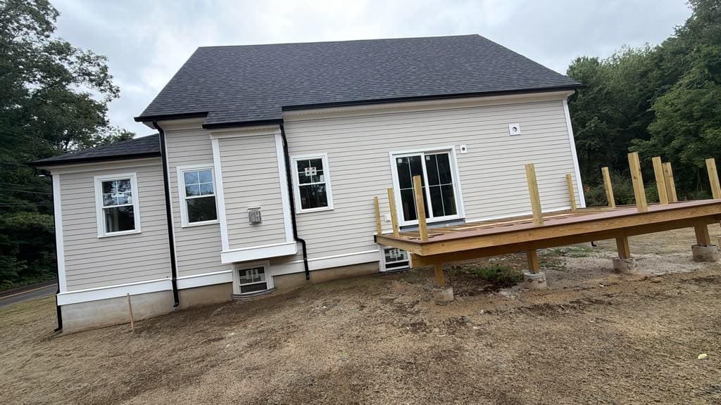Black seamless gutter running the full length of a new grey-sided house, downspout at the corner