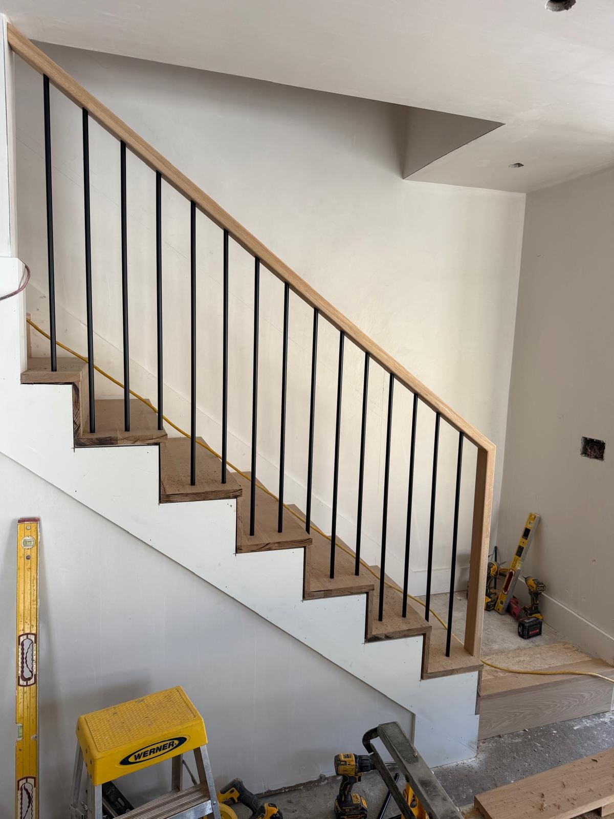 Finished white oak handrail with square black metal balusters over oak treads