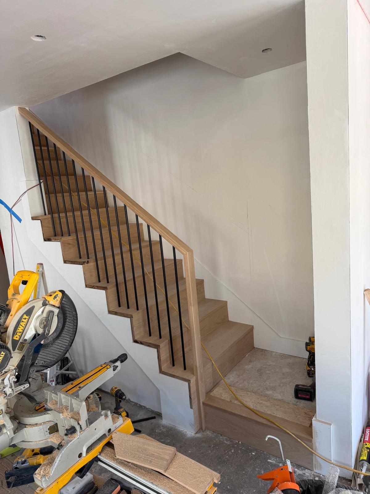 Full flight of oak stairs with black balusters and an oak rail