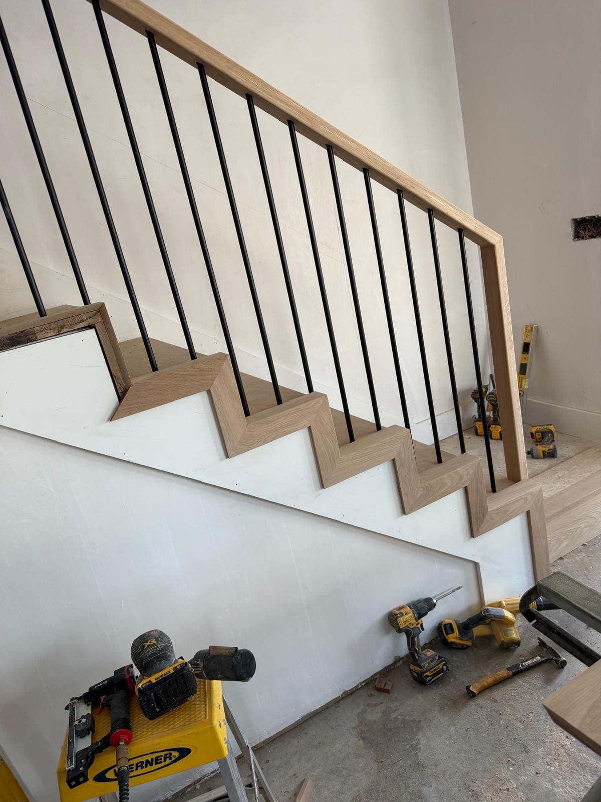 Oak rail and black balusters carried around a landing